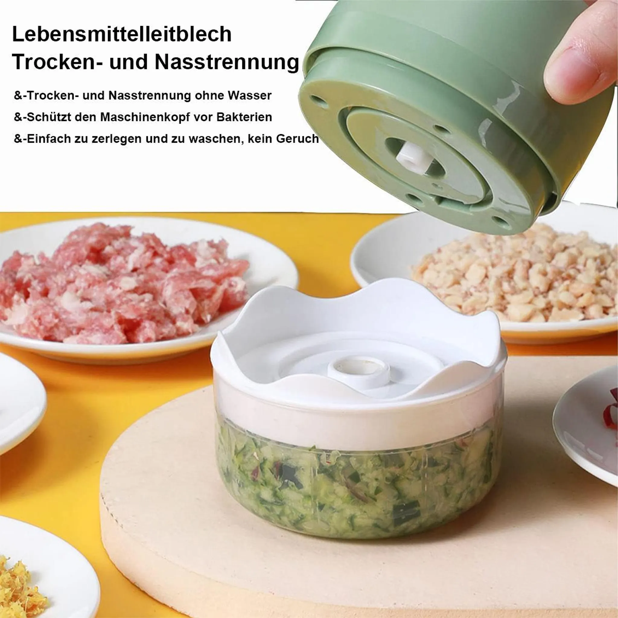 Grüner Mini-Zerkleinerer mit gehacktem Gemüse in einem Glasbehälter, daneben rohes Fleisch und Nüsse.