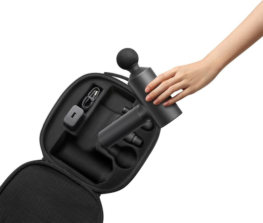 Eine Hand hält einen schwarzen Massagegriff über einer offenen schwarzen Tasche mit Ladegerät.