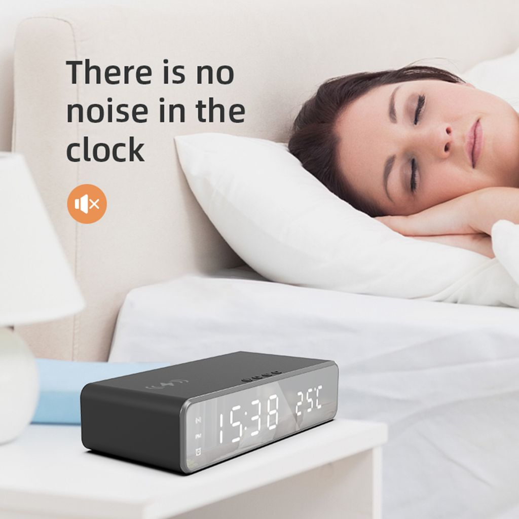 Eine Frau schläft im Bett, ein schwarzer Digitalwecker steht auf dem Nachttisch.
