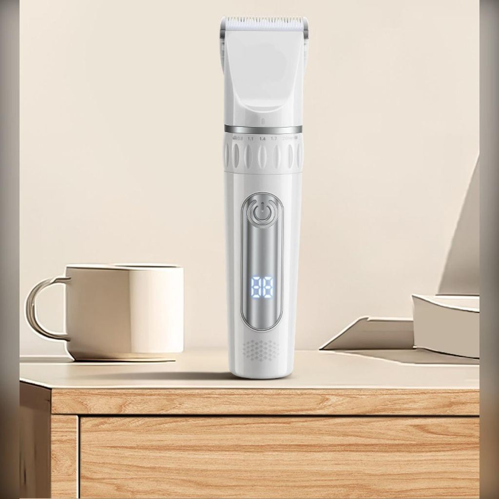 Ein weißer Haarschneider mit digitaler Anzeige steht neben einer Tasse auf einem Holztisch.