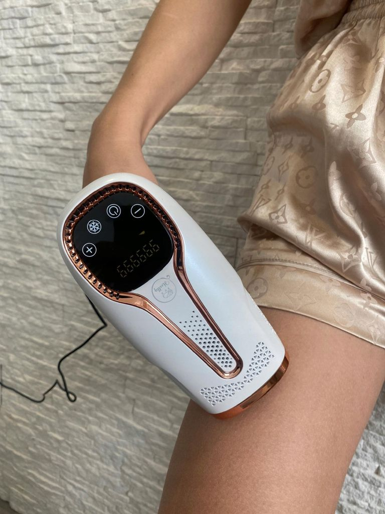 Ein weißes IPL-Haarentfernungsgerät mit Roségold-Akzenten auf einem Bein.