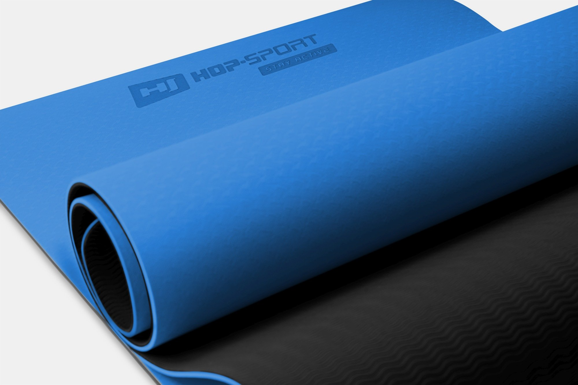 Eine blaue Yogamatte mit dem Logo "HOP-SPORT STAY ACTIVE" ist teilweise aufgerollt.