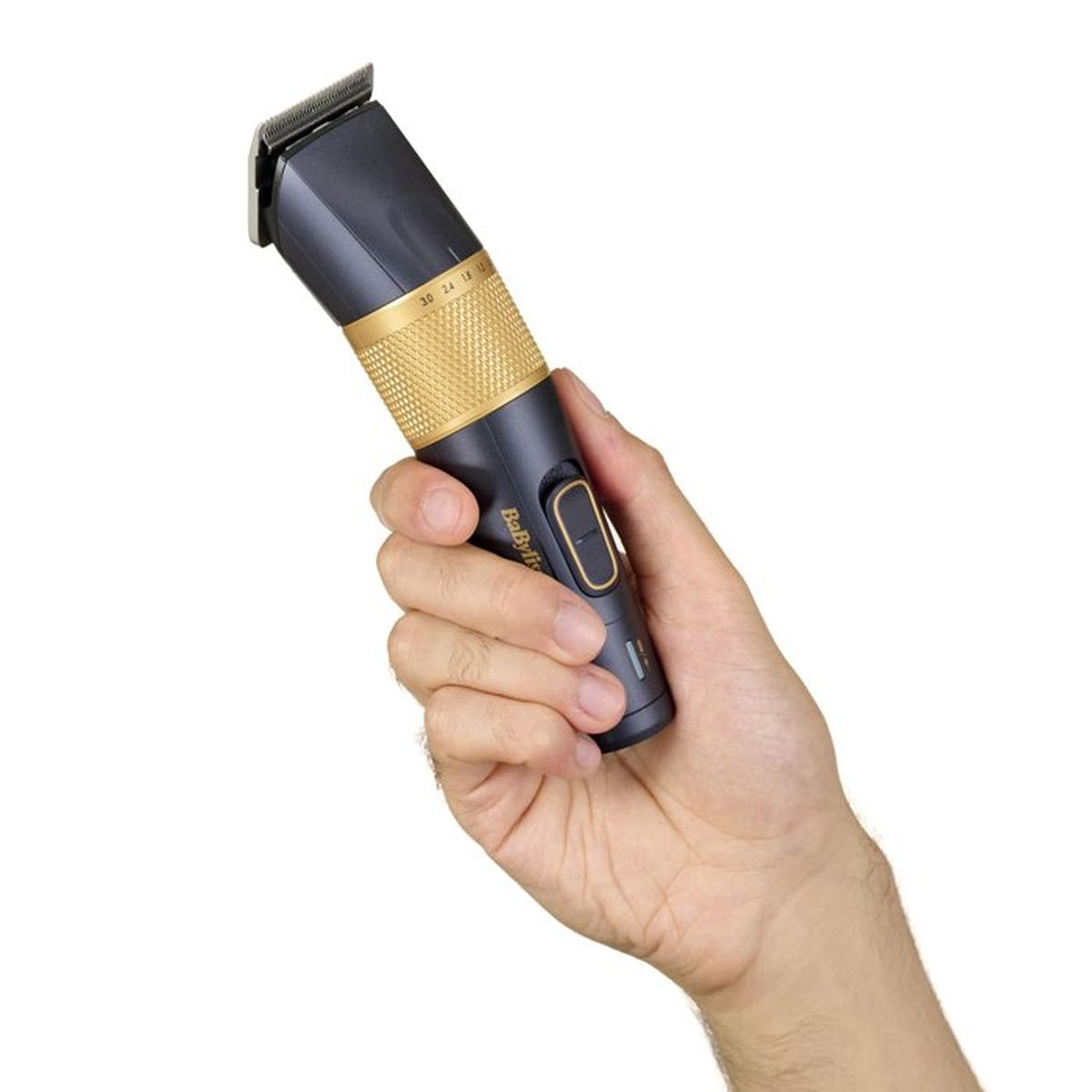 Eine Hand hält einen dunklen Haarschneider mit goldenem Ring und Einstellrad.