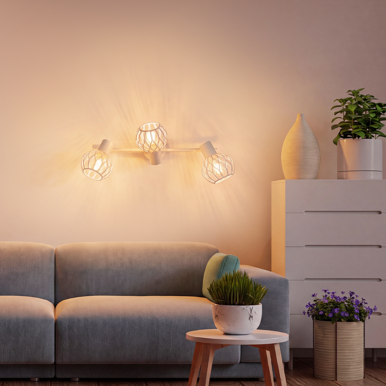 Ein graues Sofa mit Beistelltisch und Lampe, daneben eine Kommode mit Pflanzen.