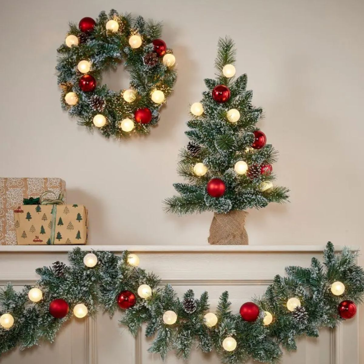 Frosted Christmas wreath, mini tree, garland, and gifts on a shelf.