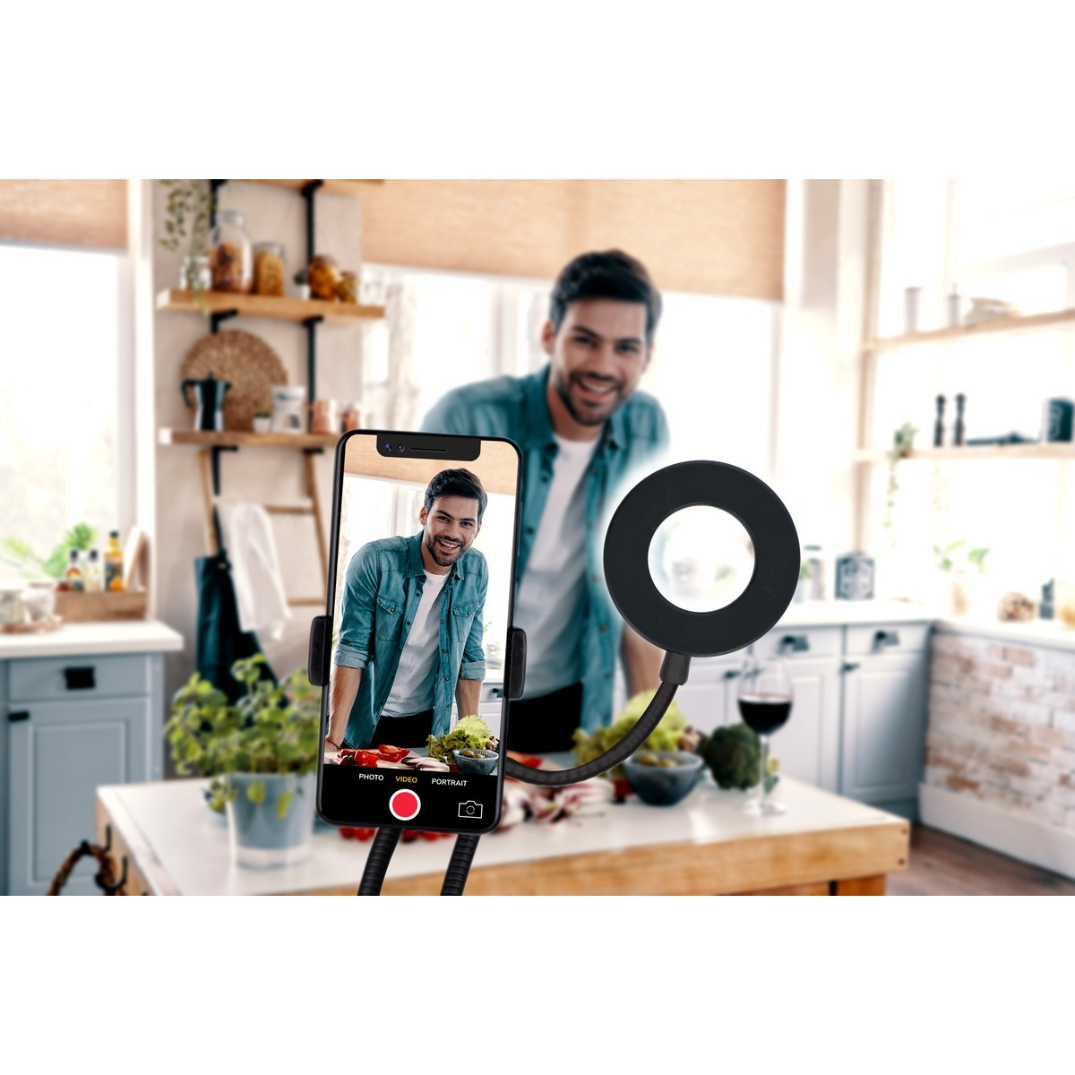 Man filming himself in a kitchen with a ring light and phone.