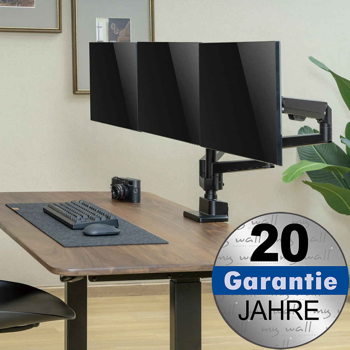 Ein Schreibtisch mit drei Monitoren, Tastatur, Maus und Kamera. Mit Garantie-Logo.