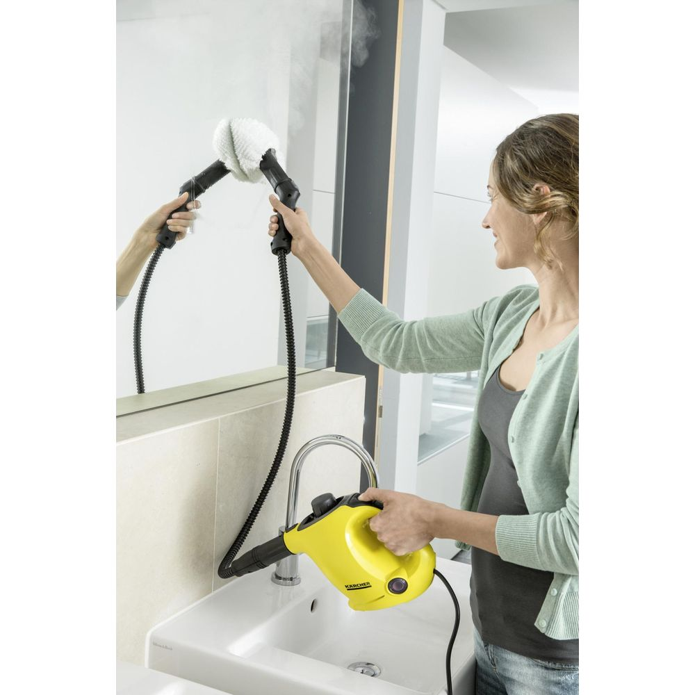Eine Frau reinigt einen Spiegel mit einem Dampfreiniger über einem Waschbecken.