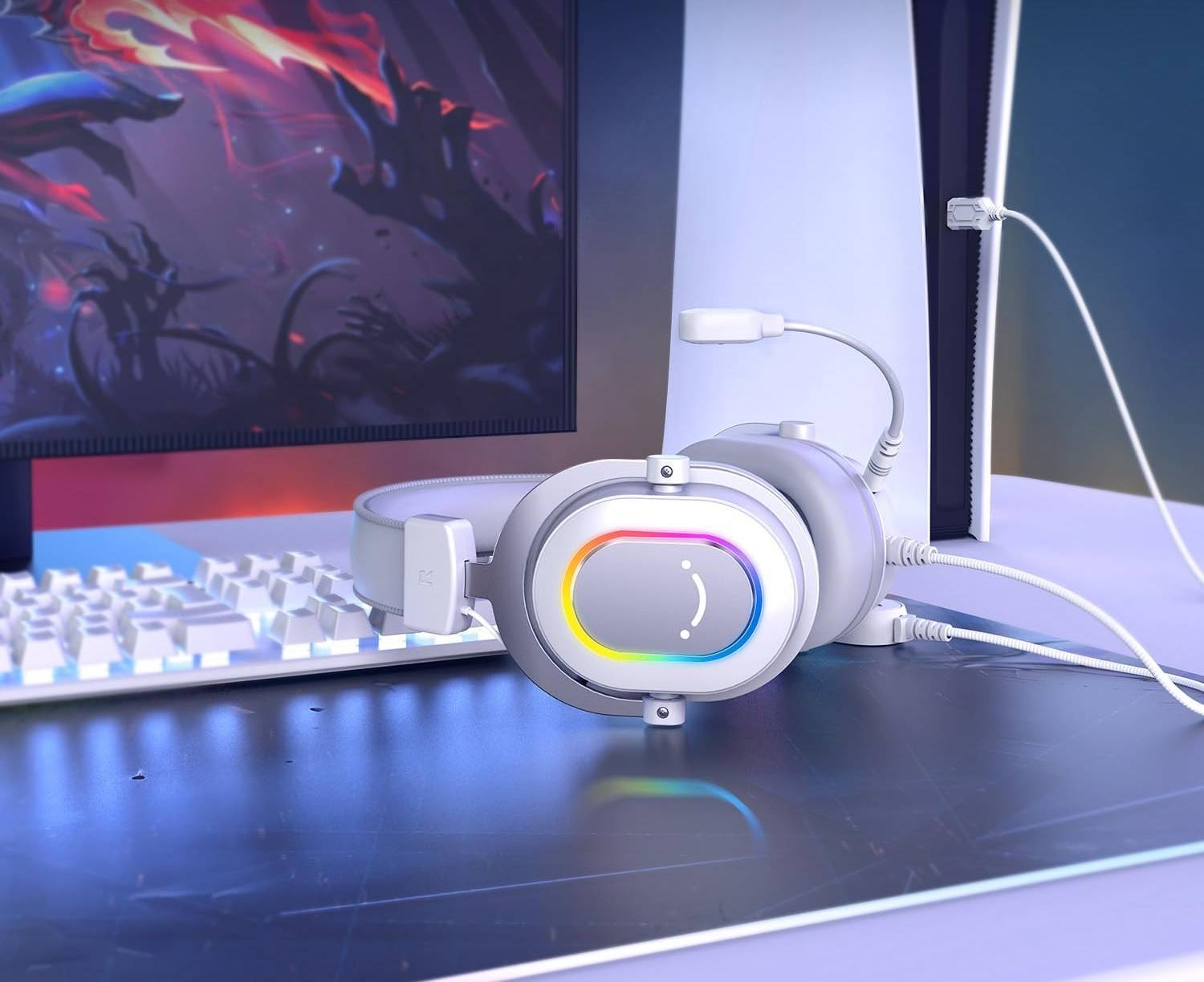 Białe słuchawki gamingowe z podświetleniem RGB obok klawiatury i konsoli.