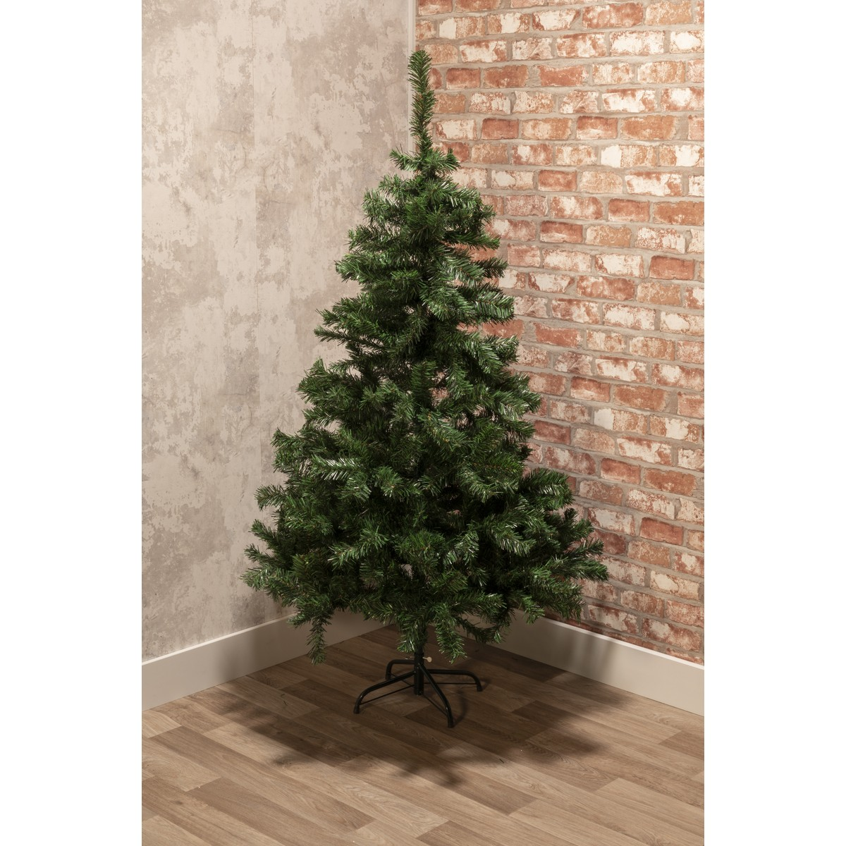 A green artificial Christmas tree with a black stand, on a wooden floor.