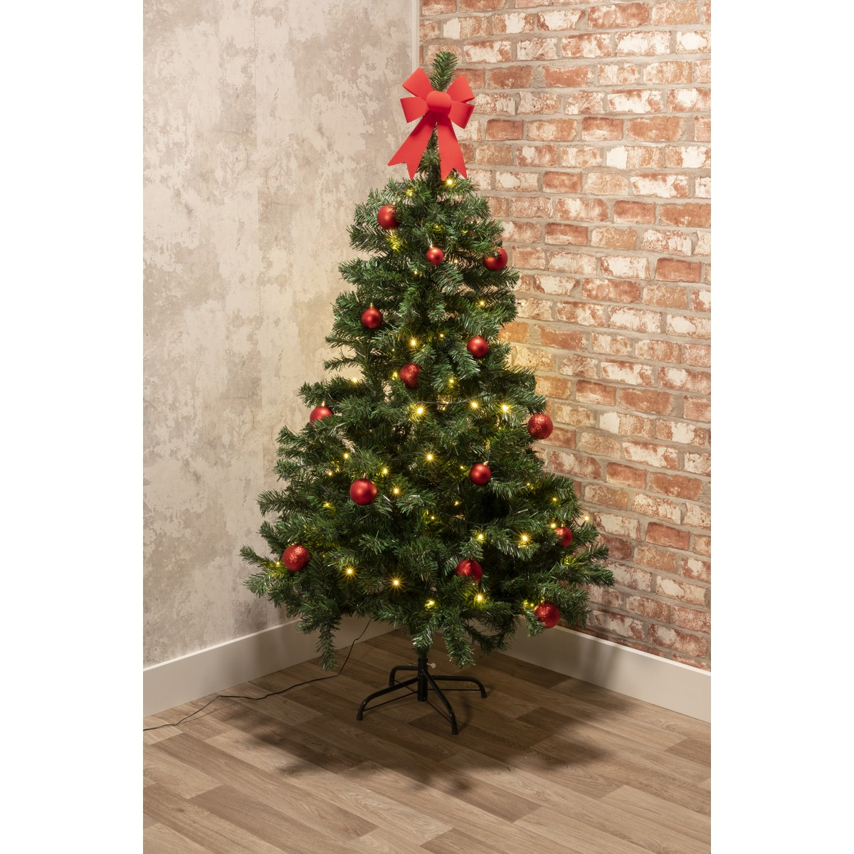 A decorated Christmas tree with red baubles and lights, topped with a red bow.