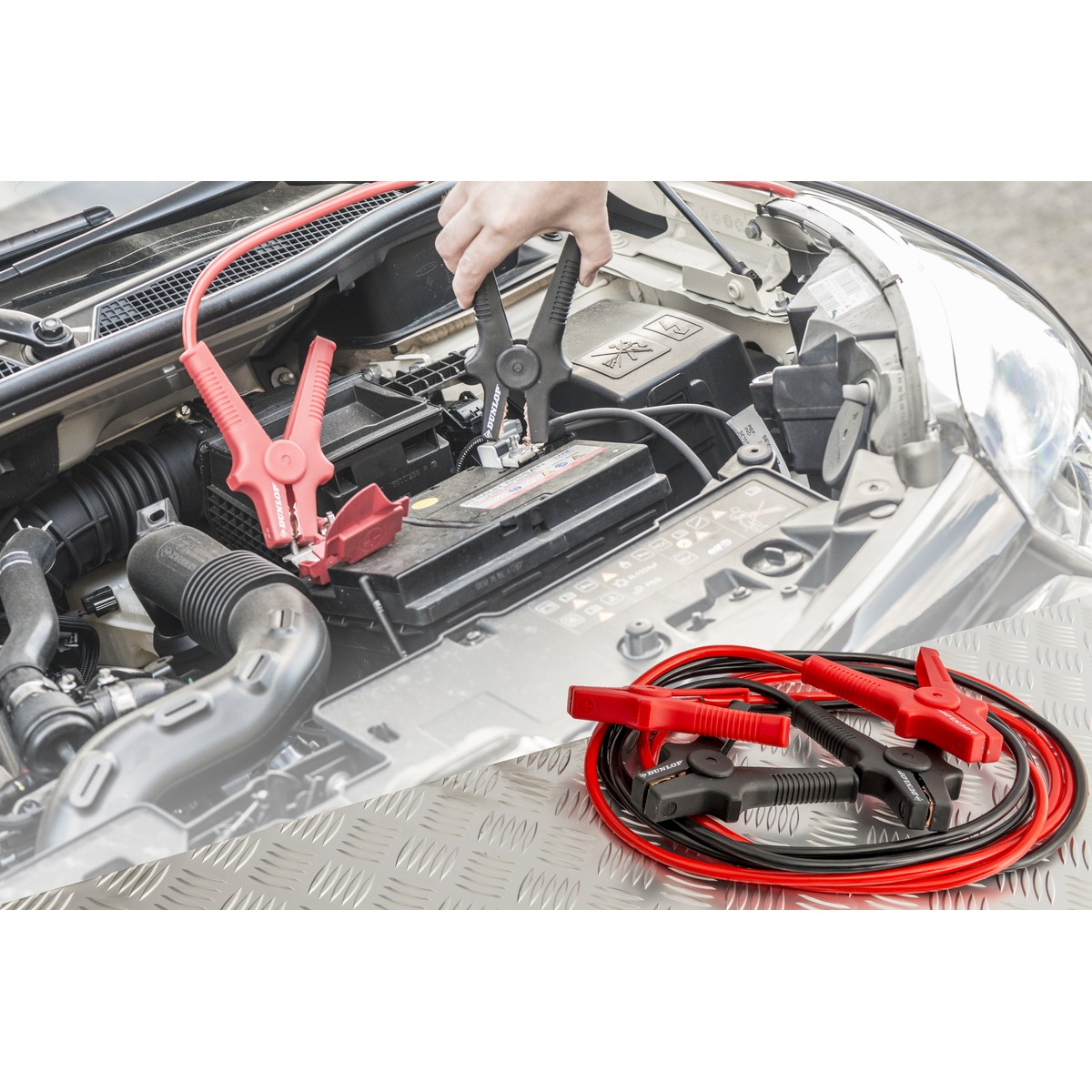 Person connecting jumper cables to a car battery.