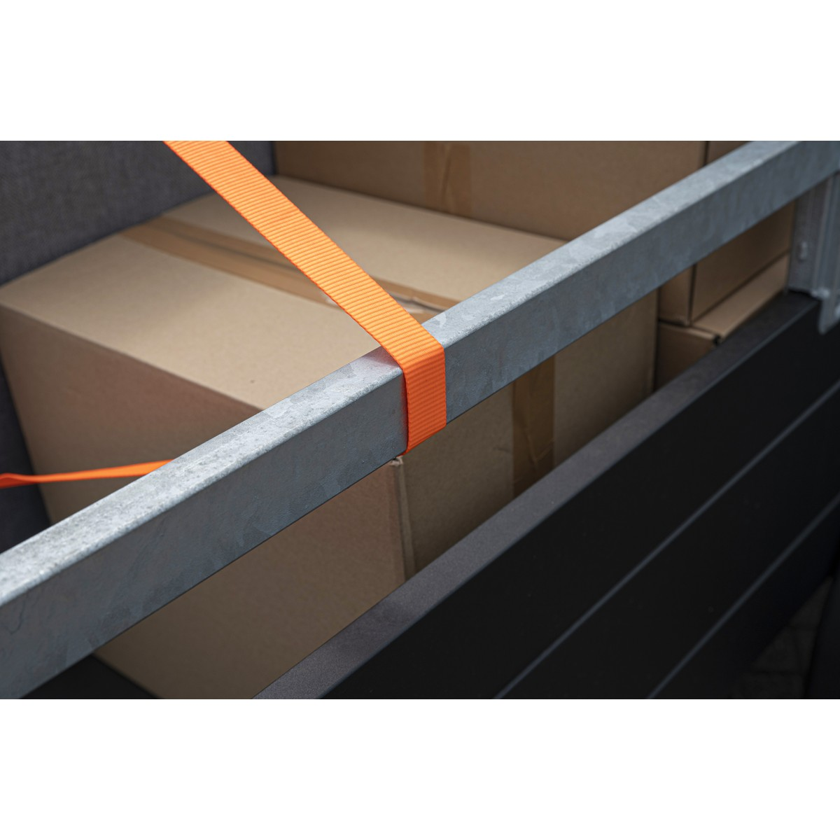 Orange strap secures cardboard boxes within a metal frame.