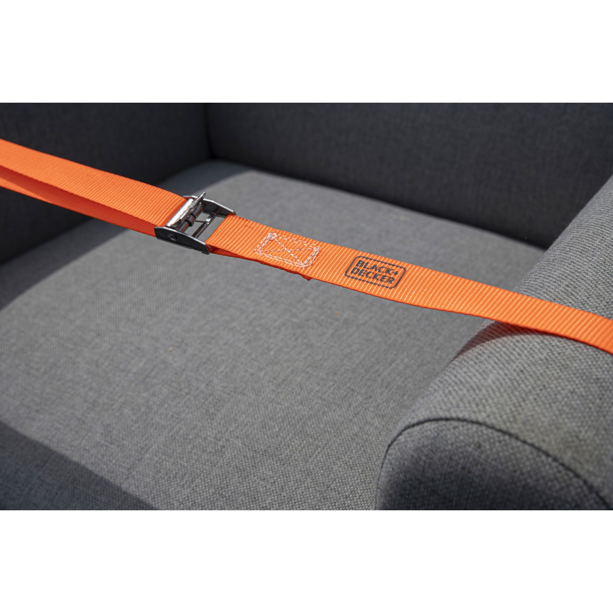 Orange strap with Black+Decker logo secured to gray armchair.