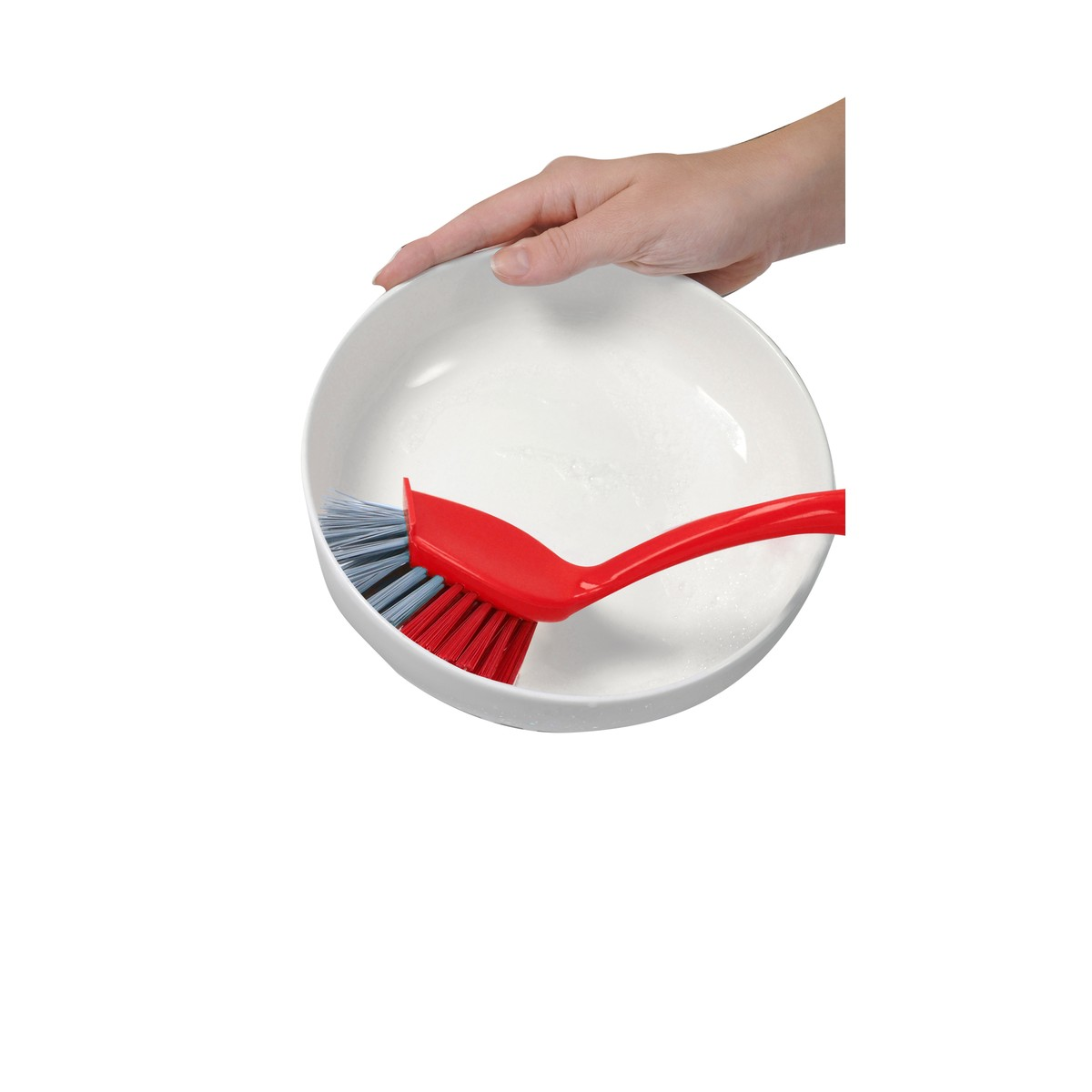 Una mano sostiene un cuenco blanco con un cepillo rojo y azul dentro.