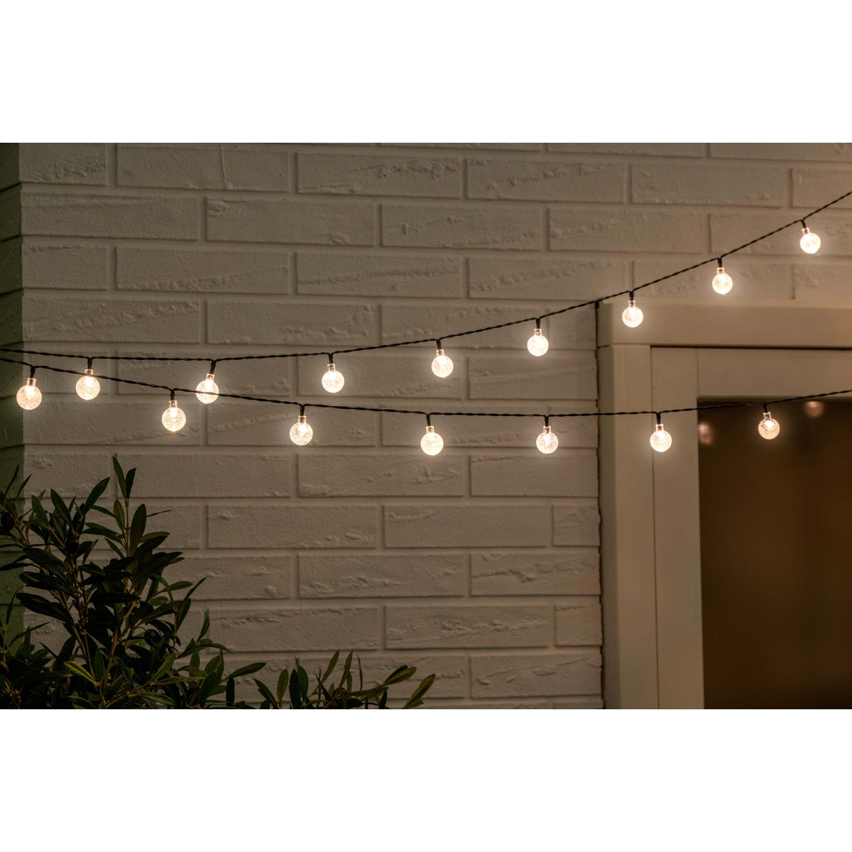 String lights with glass bulbs glow against a brick wall.
