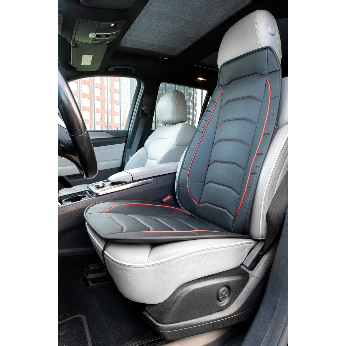 Black and red massage seat cover on a grey leather car seat.