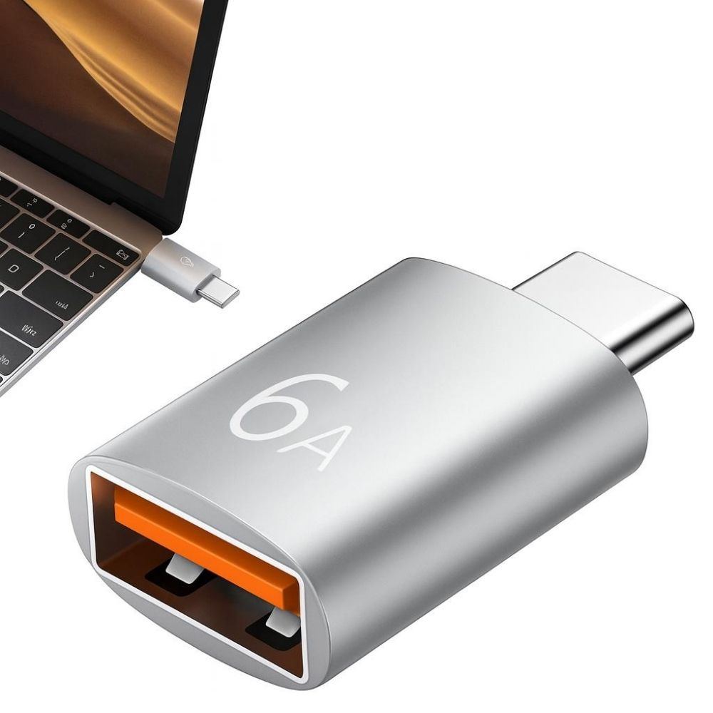 Turuncu portlu gümüş USB-C adaptörü, bir dizüstü bilgisayarın yanında.