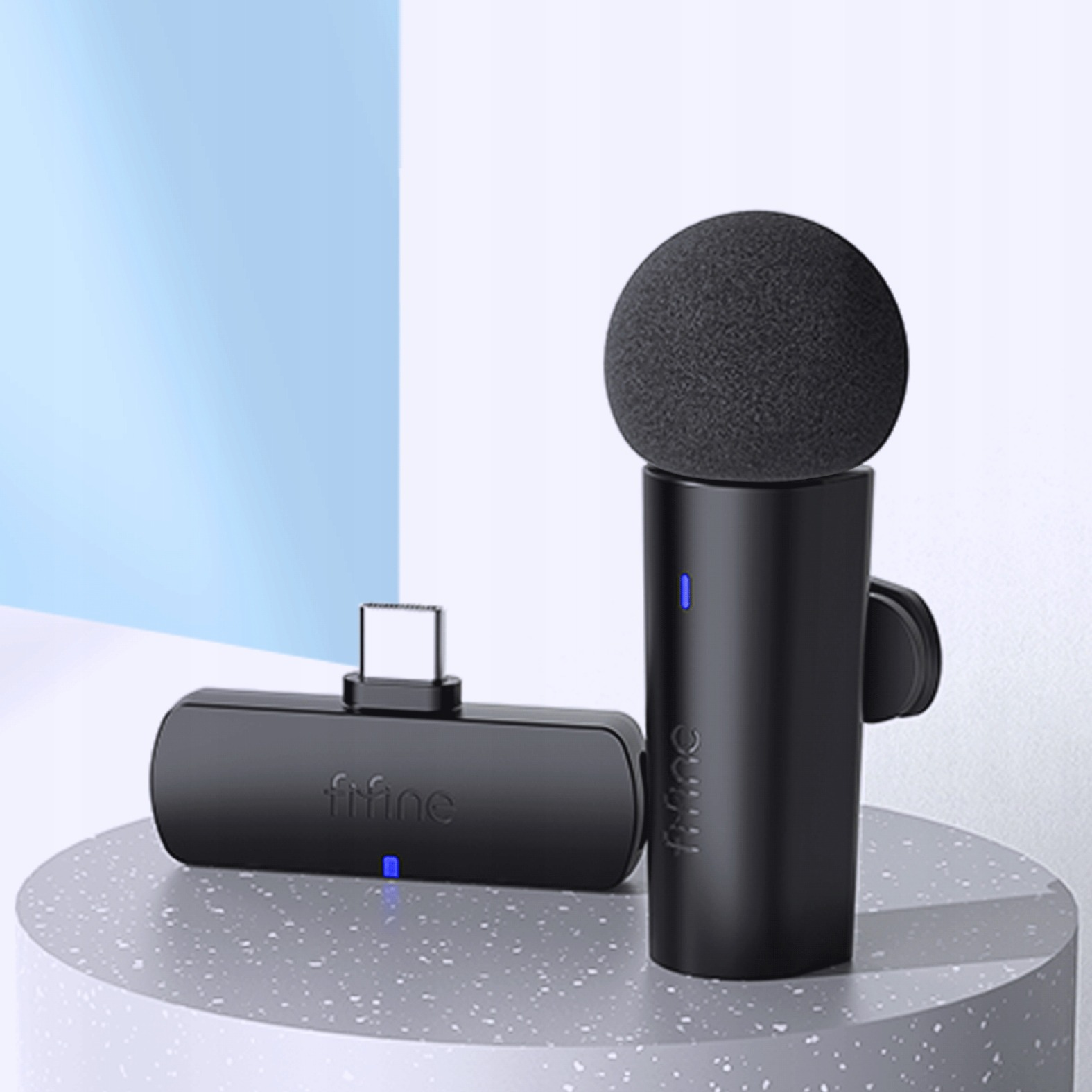Dwa czarne mikrofony z złączem USB-C na szarym stojaku.