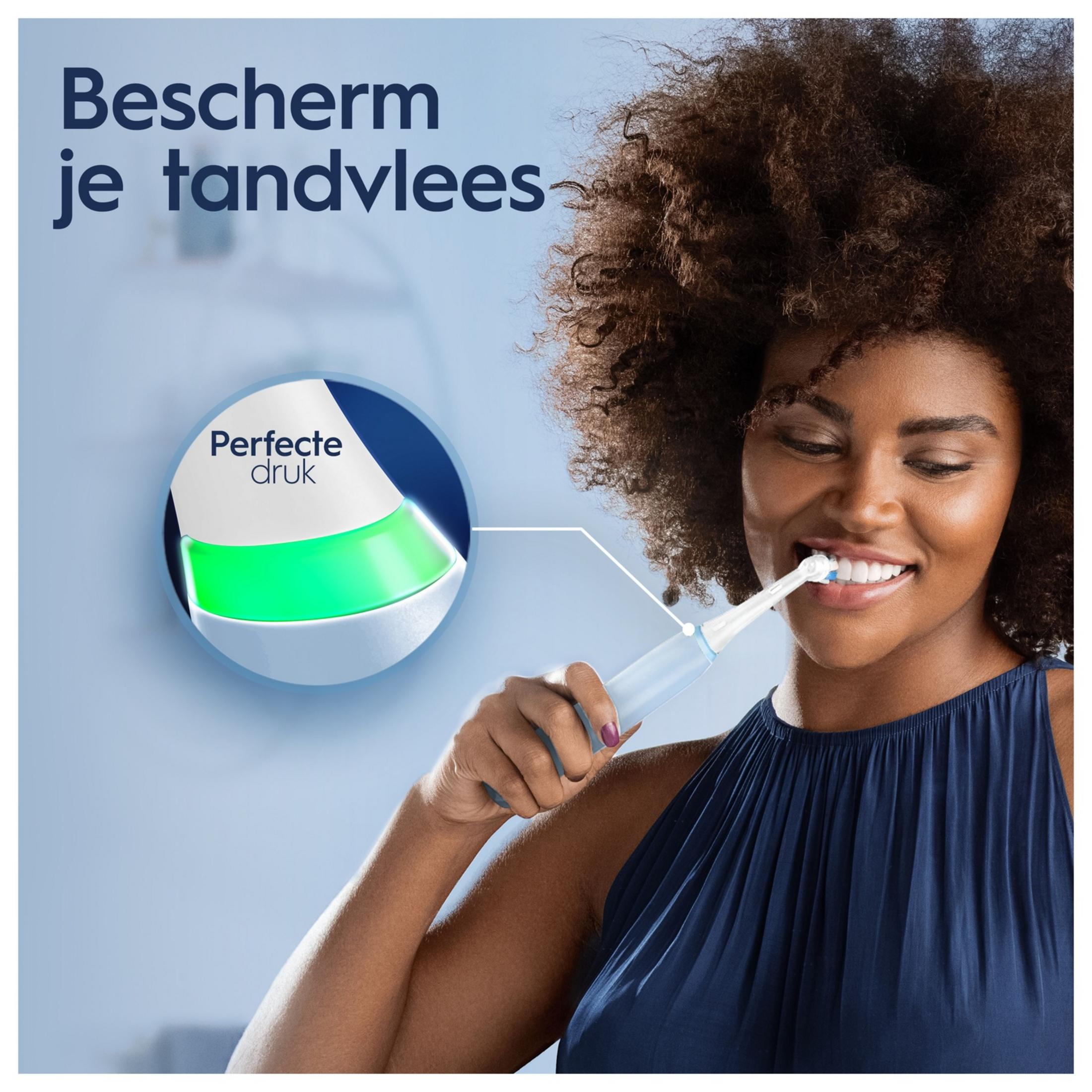 Donna si lava i denti con spazzolino elettrico, luce verde indica pressione perfetta.