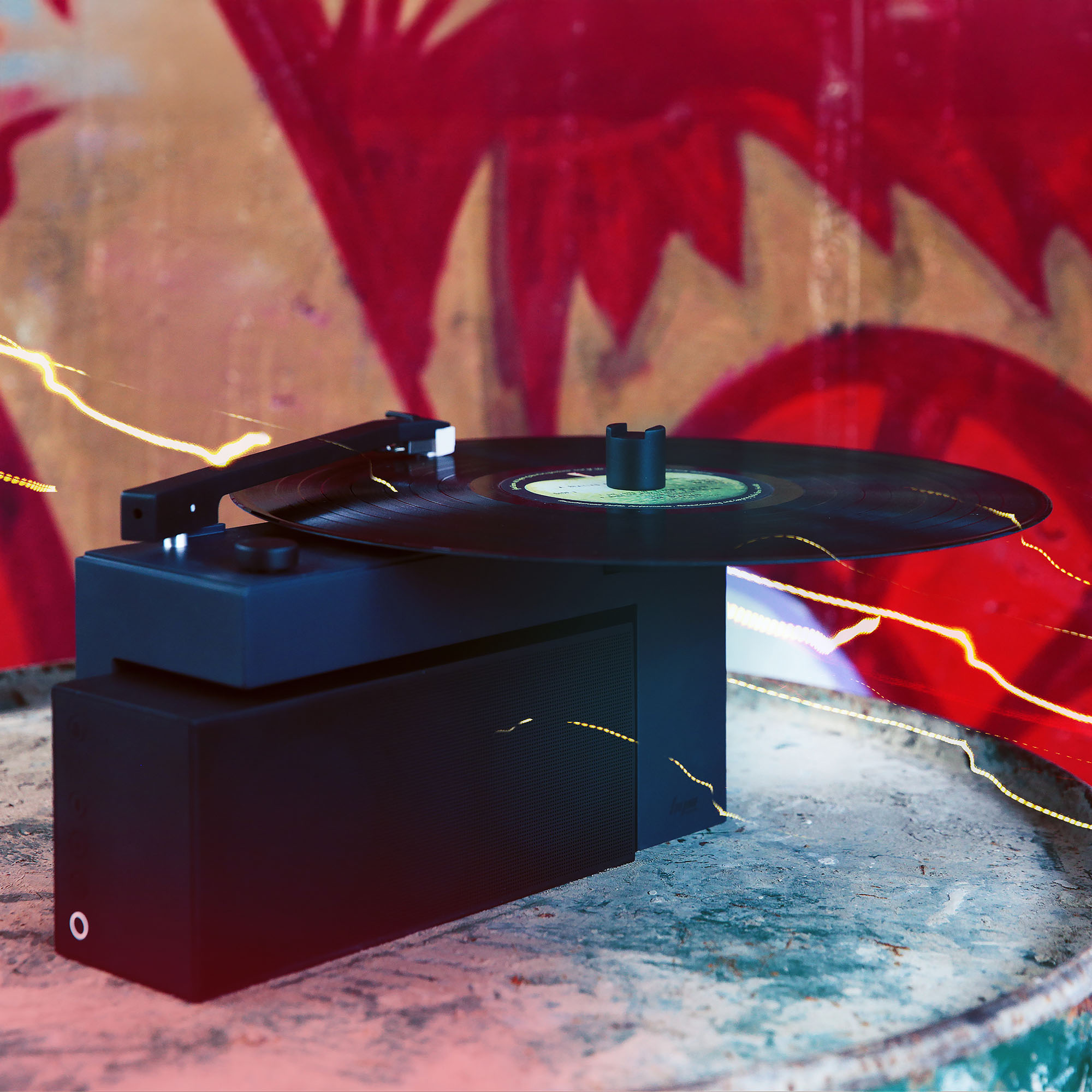 Vinil plaklı siyah pikap, grafitinin önündeki paslı metal yüzeyde duruyor.