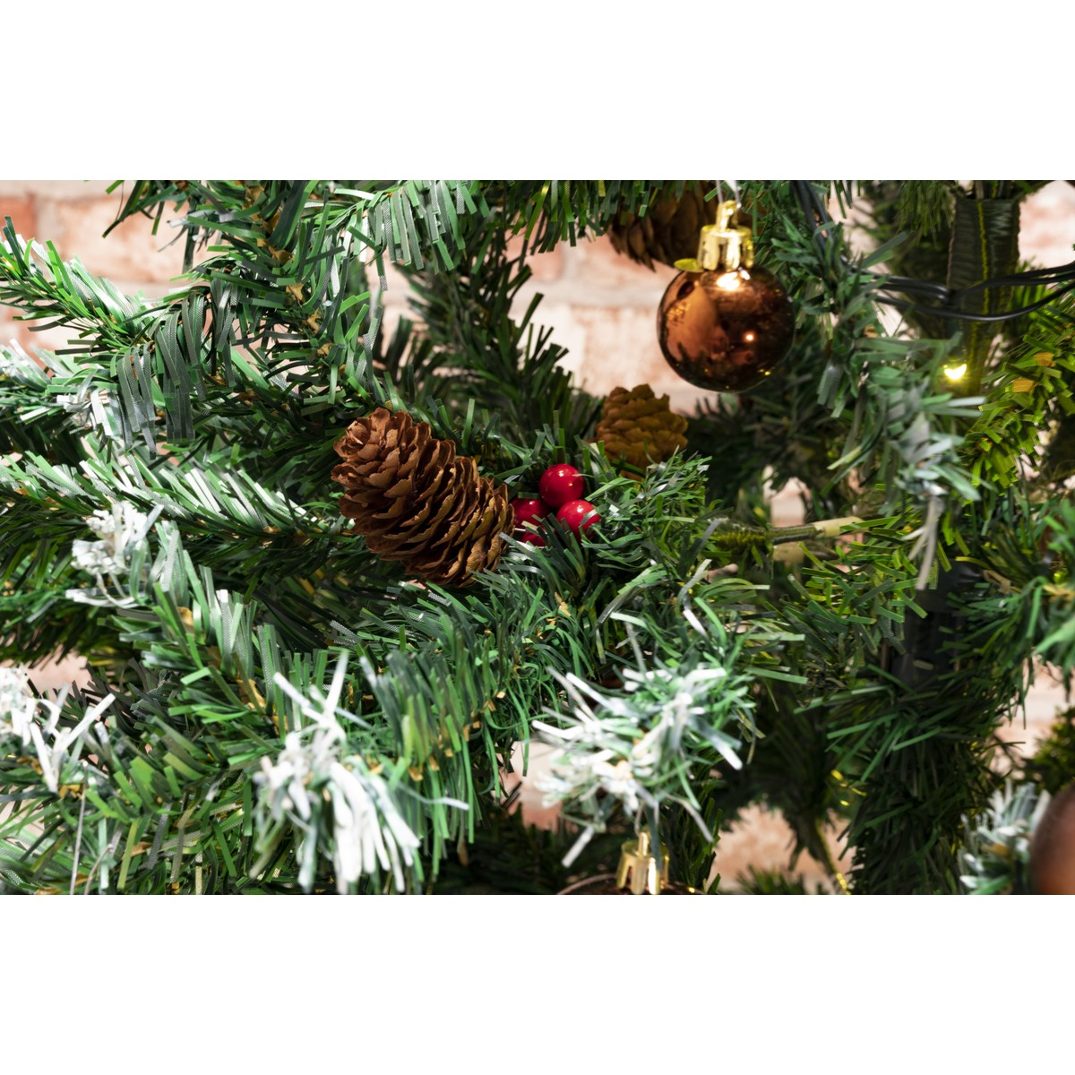 Close up of a decorated Christmas tree branch with pine cones, red berries, and ornaments.