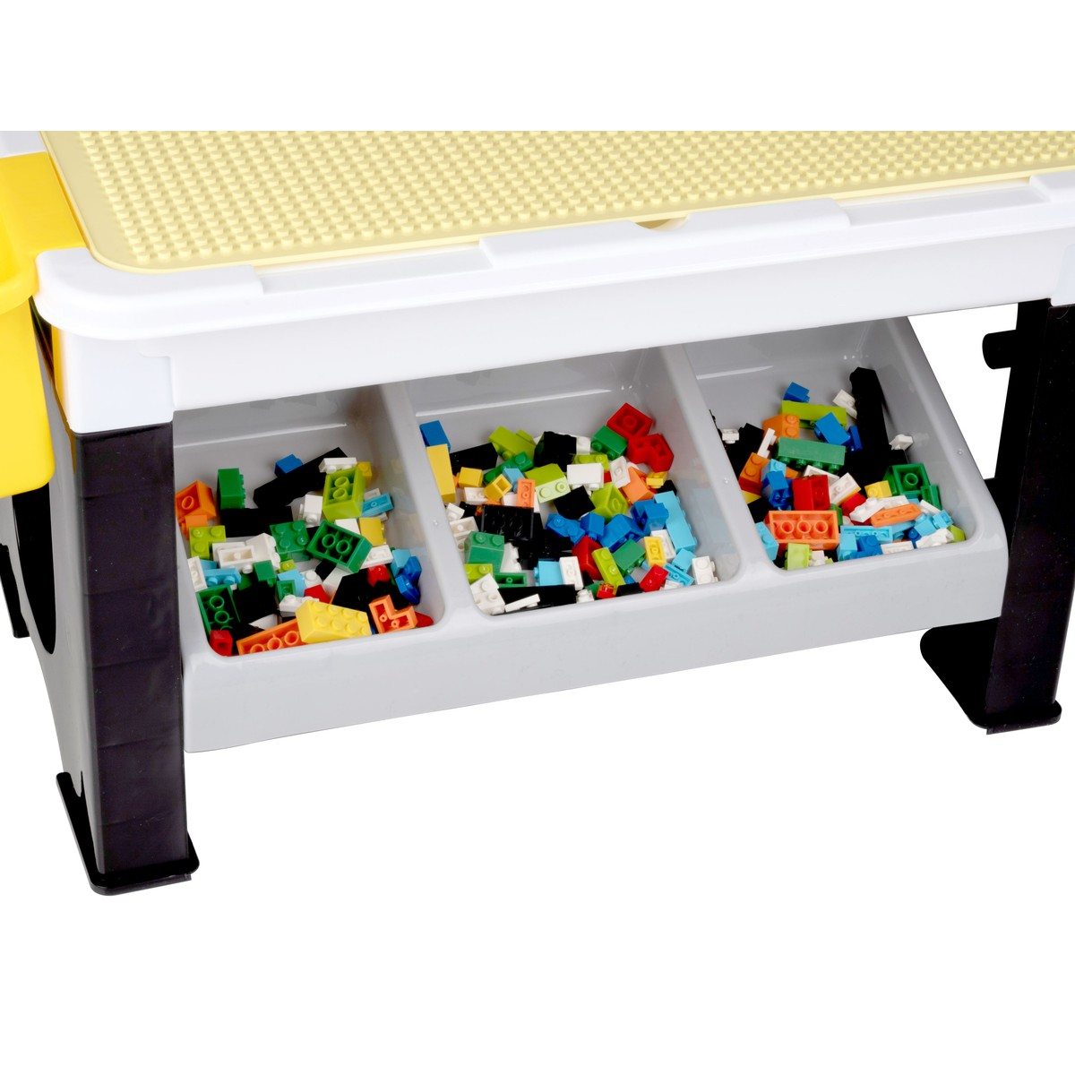 A play table with a yellow building plate and three compartments full of colorful building blocks.
