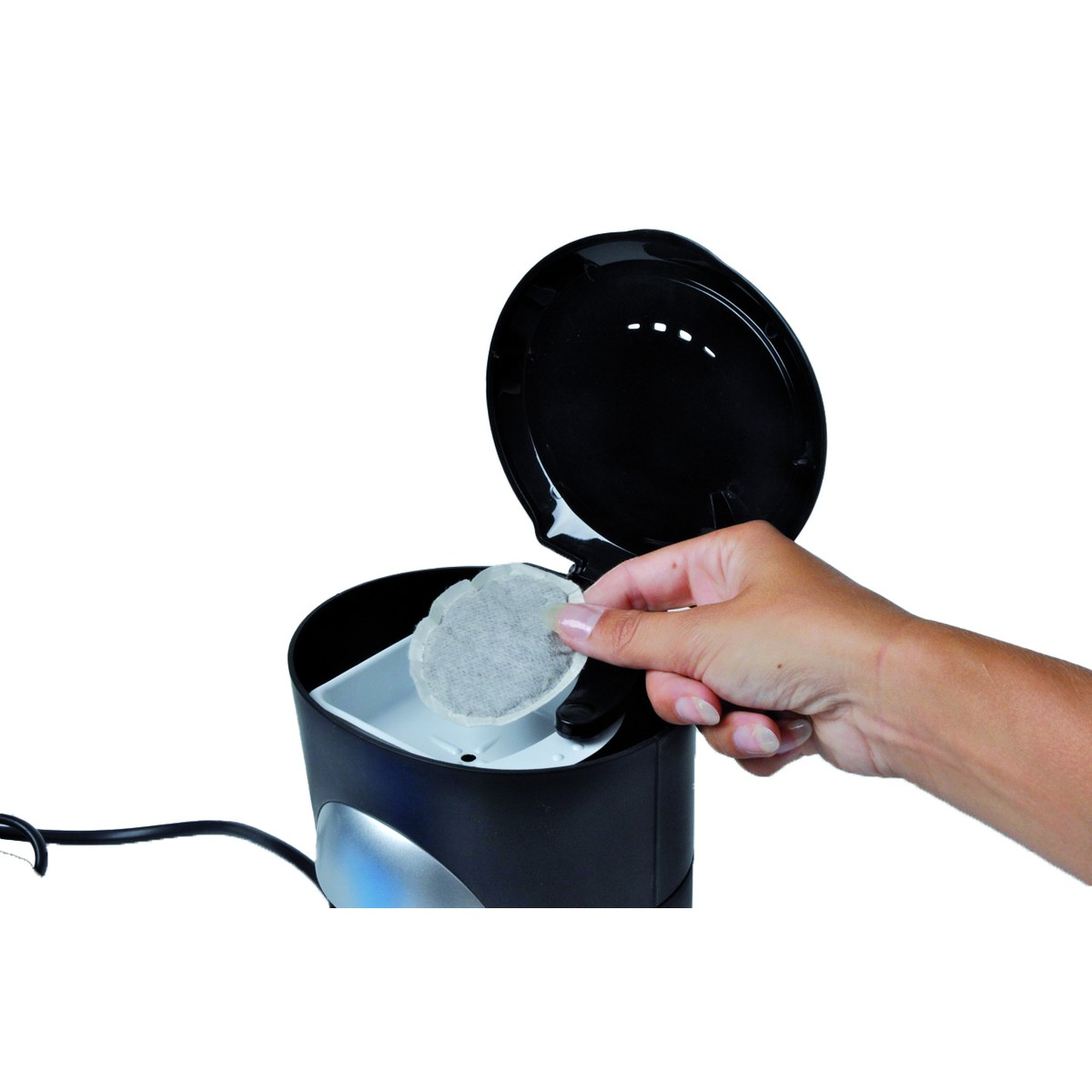 A hand places a coffee pod into a coffee maker.