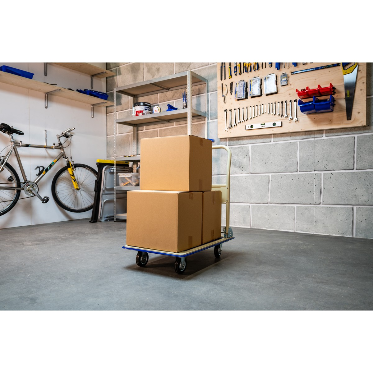 A hand truck with two cardboard boxes on a concrete floor in a garage.