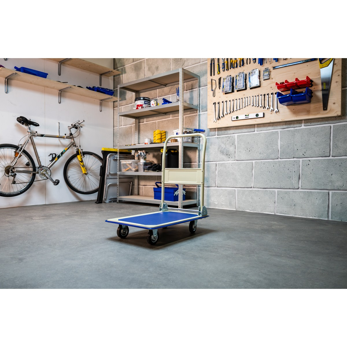 A blue trolley cart sits in a garage next to a bicycle and shelves.