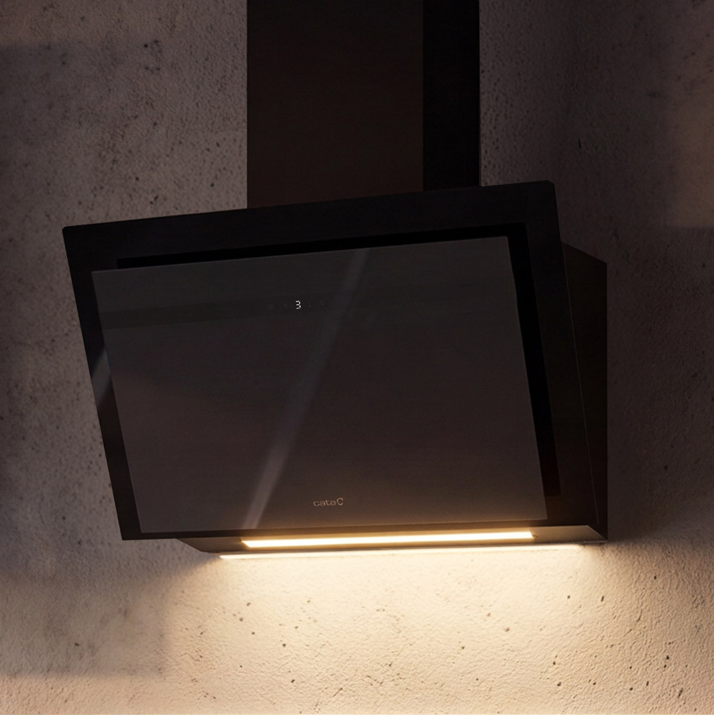 Campana extractora negra con frente de cristal y luz sobre pared de hormigón.