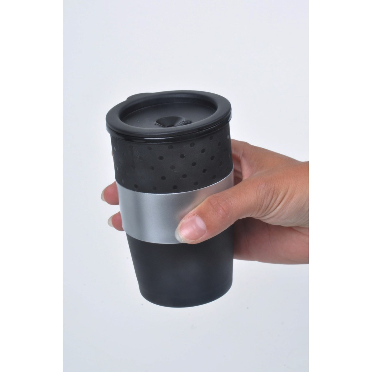A hand holds a black travel mug with a silver band and black lid.