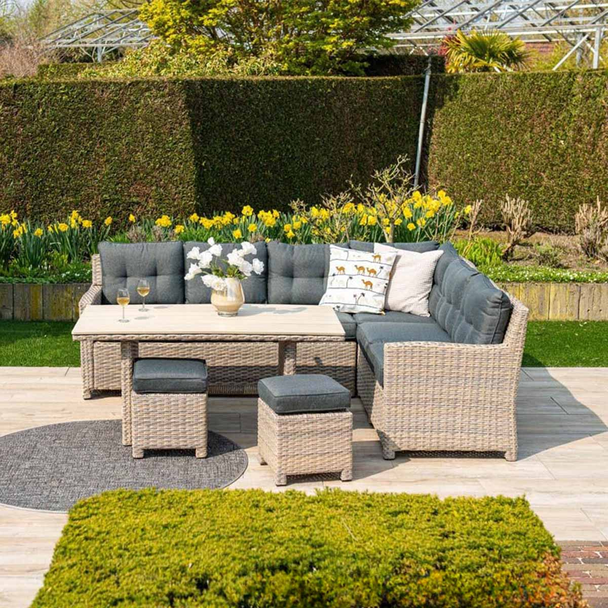 Wicker patio set with table, cushions, and ottomans on a deck.