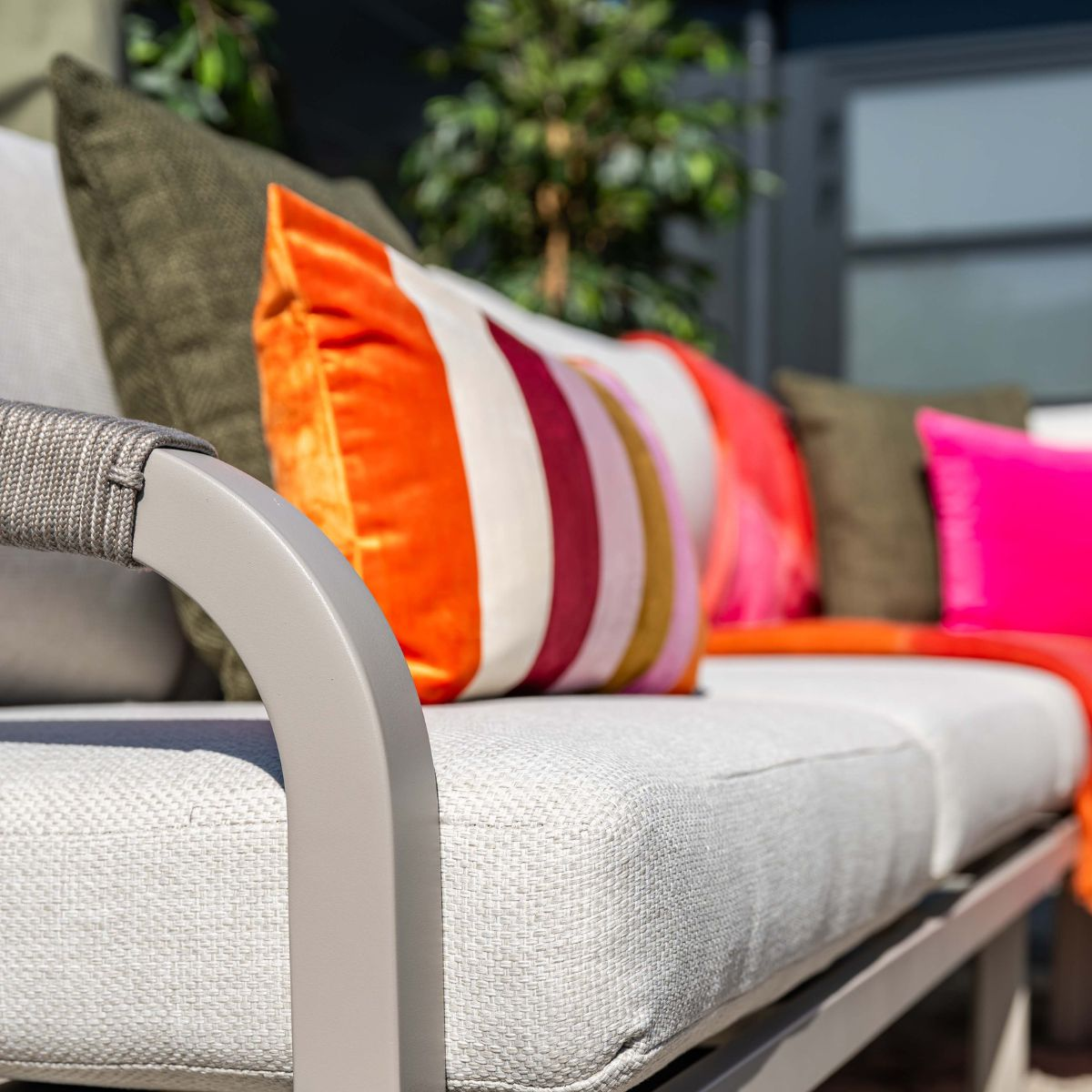 A modern grey sofa with colorful pillows and an orange throw blanket.