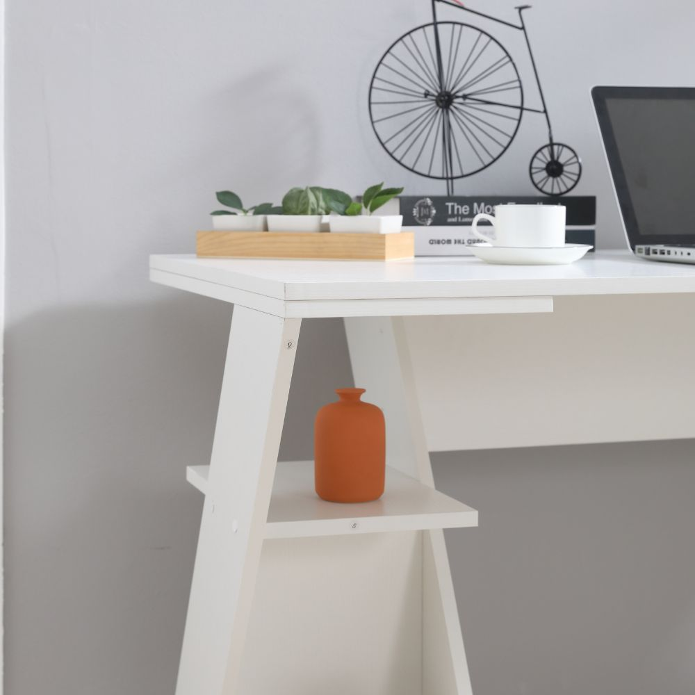 Una scrivania bianca con piante, una tazza e un laptop. Una bicicletta decorativa sul muro.