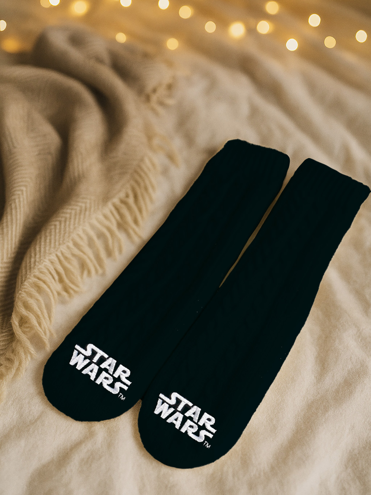 Zwei schwarze Socken mit "Star Wars"-Logo liegen auf einer Decke.