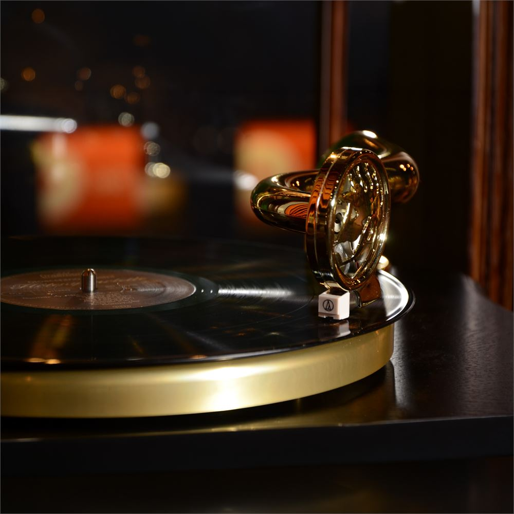 Altın bir gramofon kolu pikap üzerindeki vinil kayıtta duruyor.