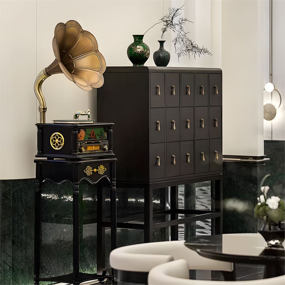 Gramofon, çekmeceli siyah bir dolabın yanında duruyor. Dolabın üstünde iki vazo var.
