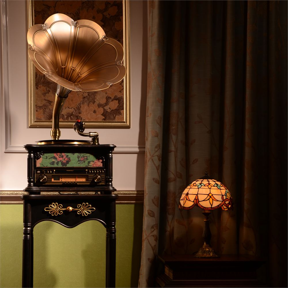 Vintage gramofon ve Tiffany lamba masada, çiçekli perdeler ve sanat eseriyle.
