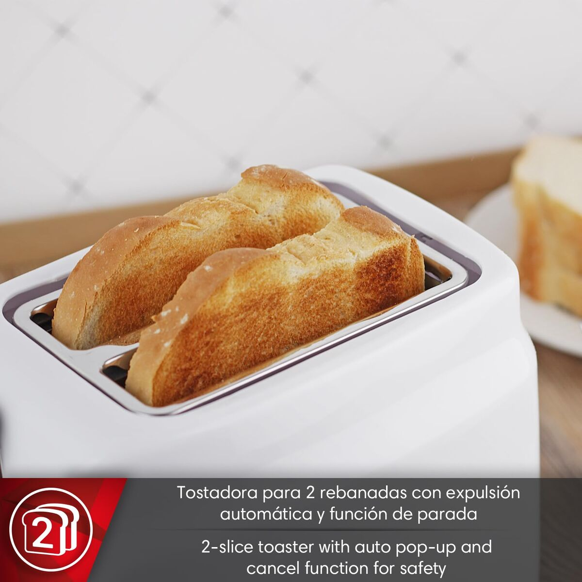 Dos tostadas doradas sobresalen de una tostadora blanca. Una rebanada de pan al fondo.