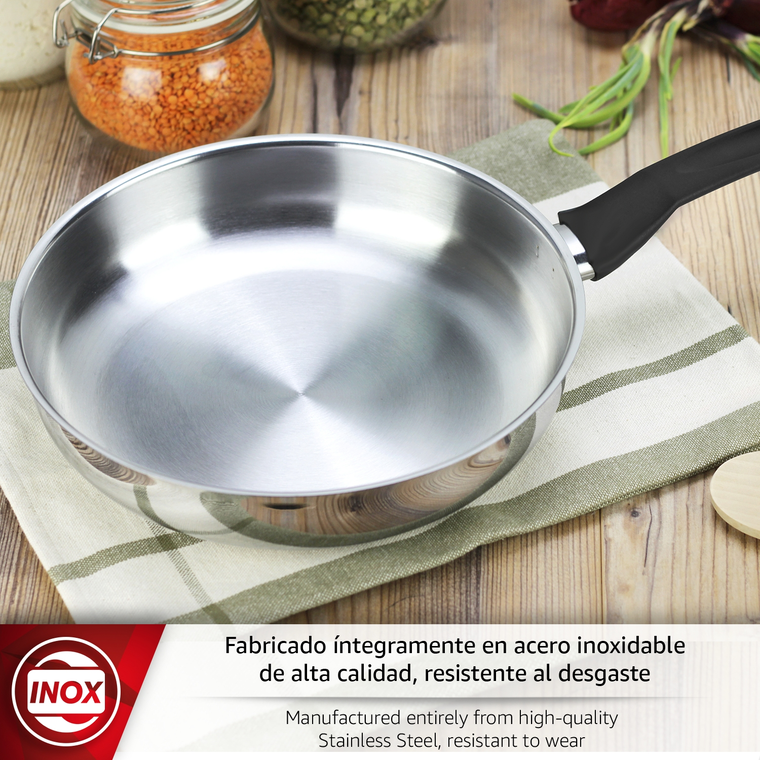 Una sartén brillante de acero inoxidable con mango negro descansa sobre un paño.