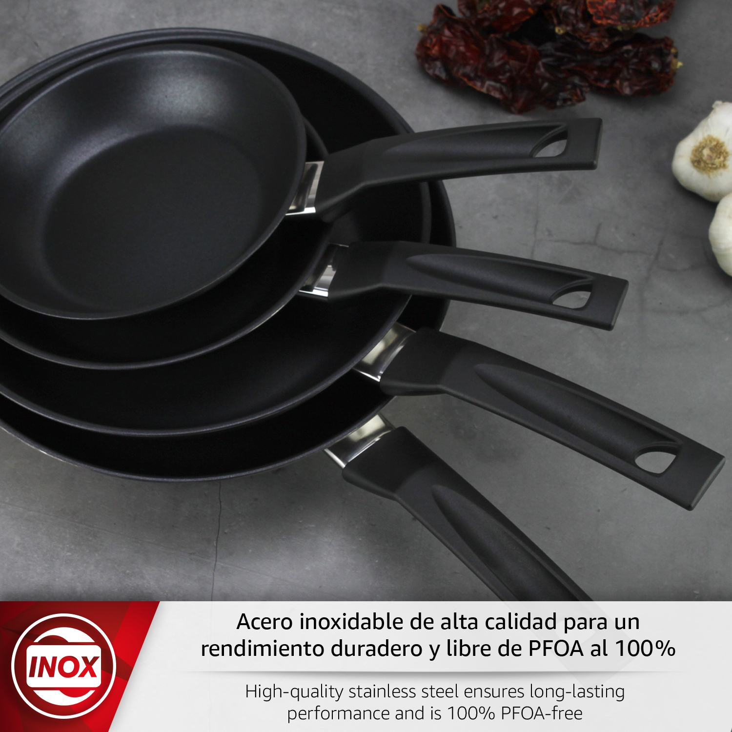 Tres sartenes negras con mangos negros sobre superficie gris con ajos y chiles.
