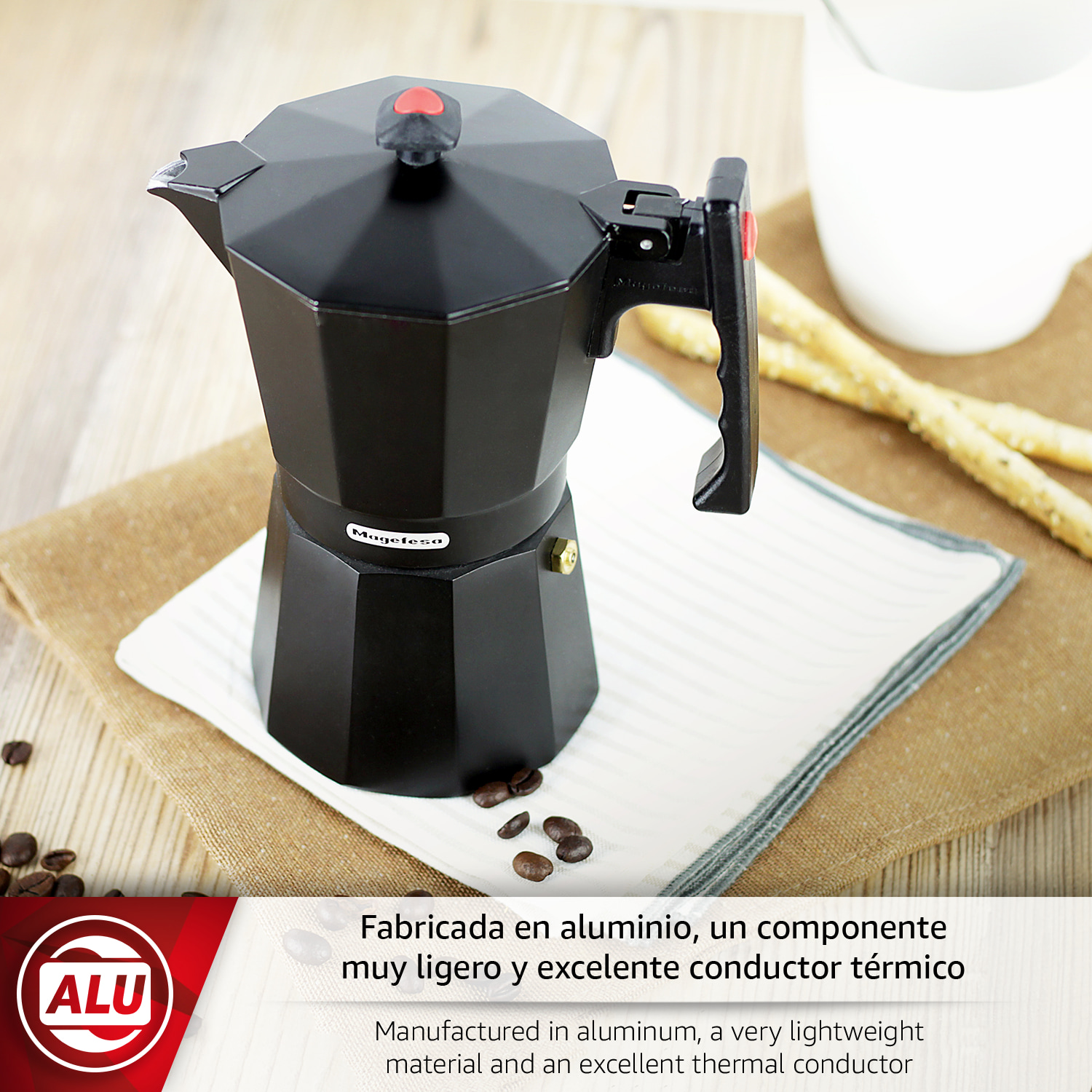 Cafetera negra de aluminio con asa, taza y palitos de pan de fondo.