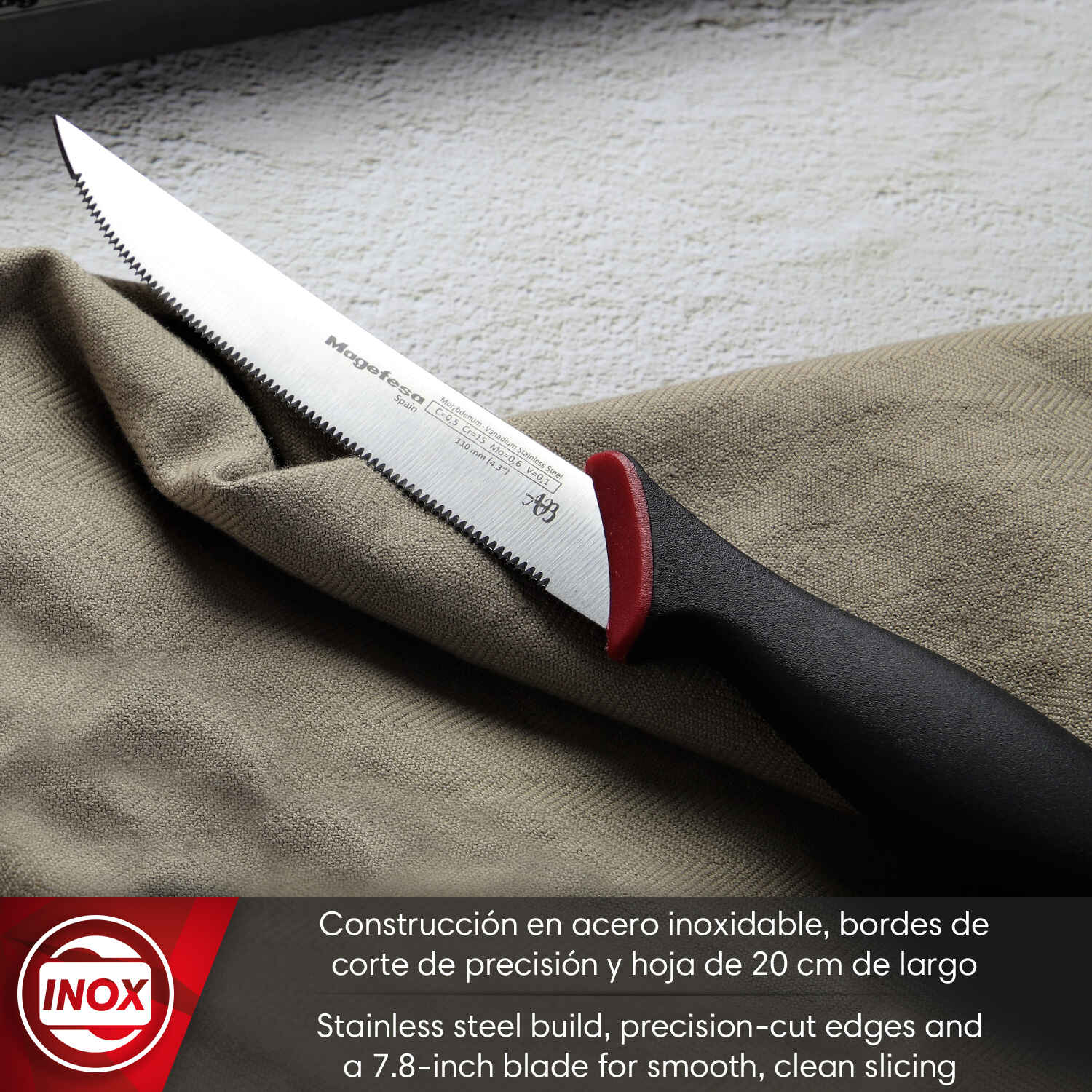 Un cuchillo de cocina serrado con mango negro descansa sobre tela. Hoja 7.8".