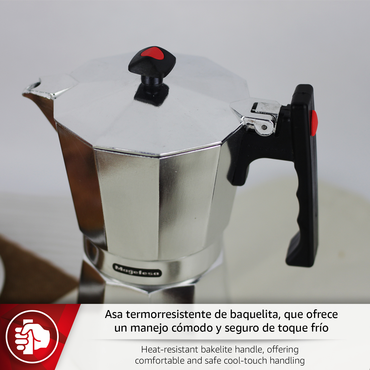 Cafetera de metal plateada con asa negra y detalle rojo.