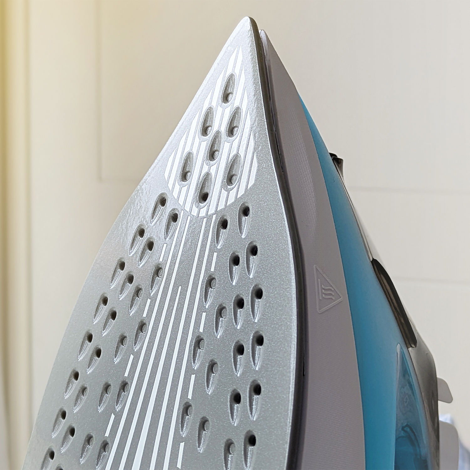 Primer plano de la suela de una plancha azul con orificios de vapor.