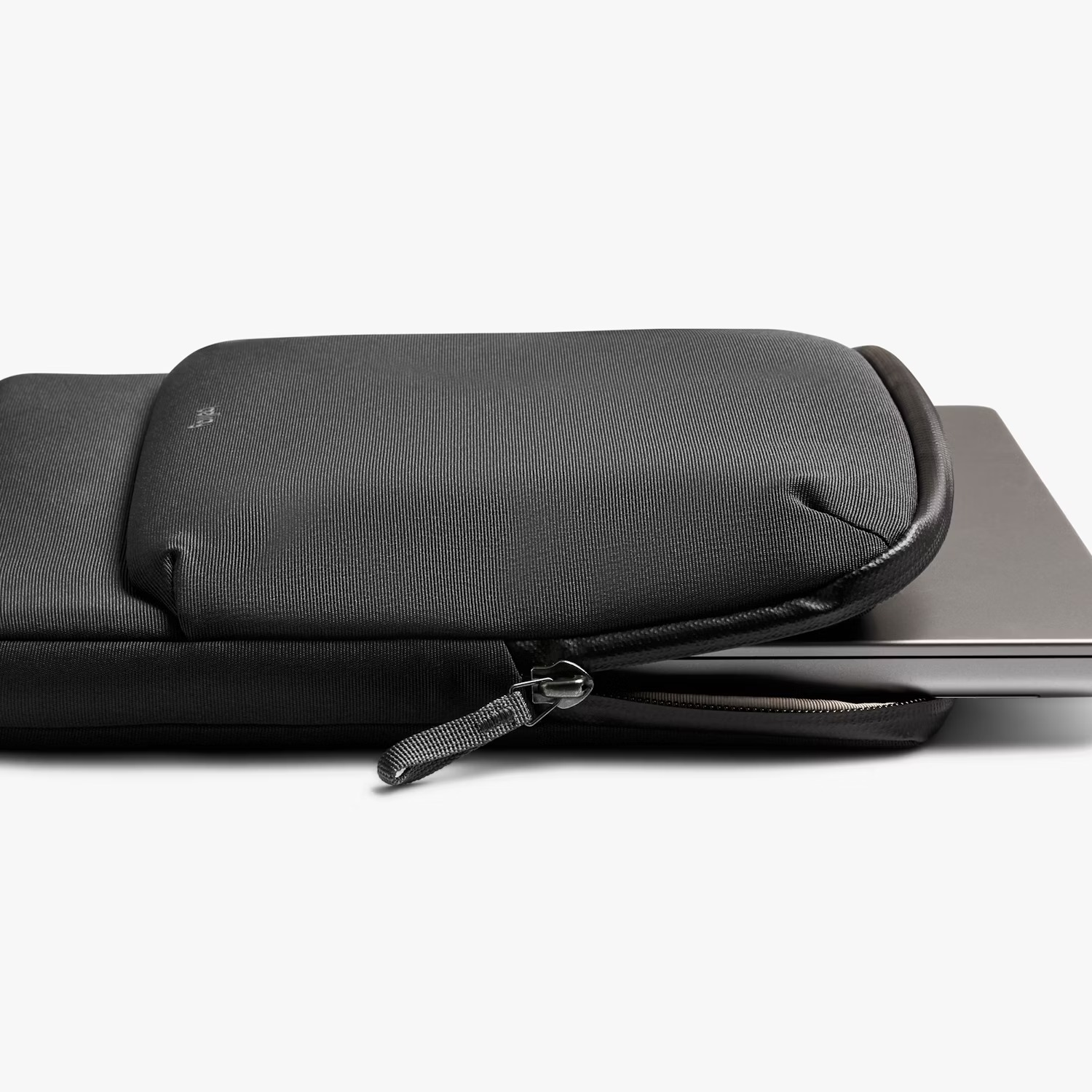 Een zwarte laptop wordt gedeeltelijk in een zwarte laptophoes geschoven.