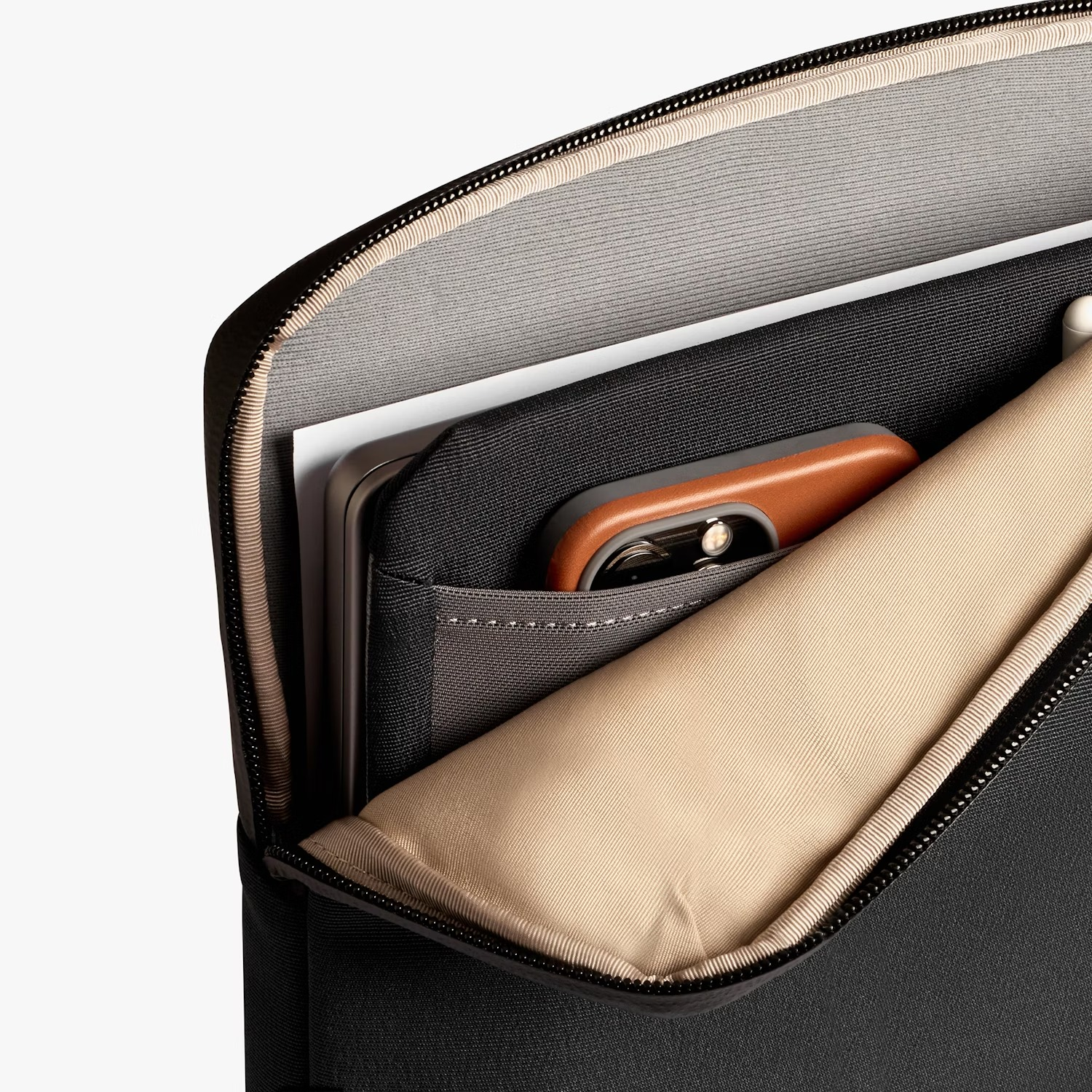 Zwarte laptoptas met open vak, tablet en bruine telefoon met hoes erin.