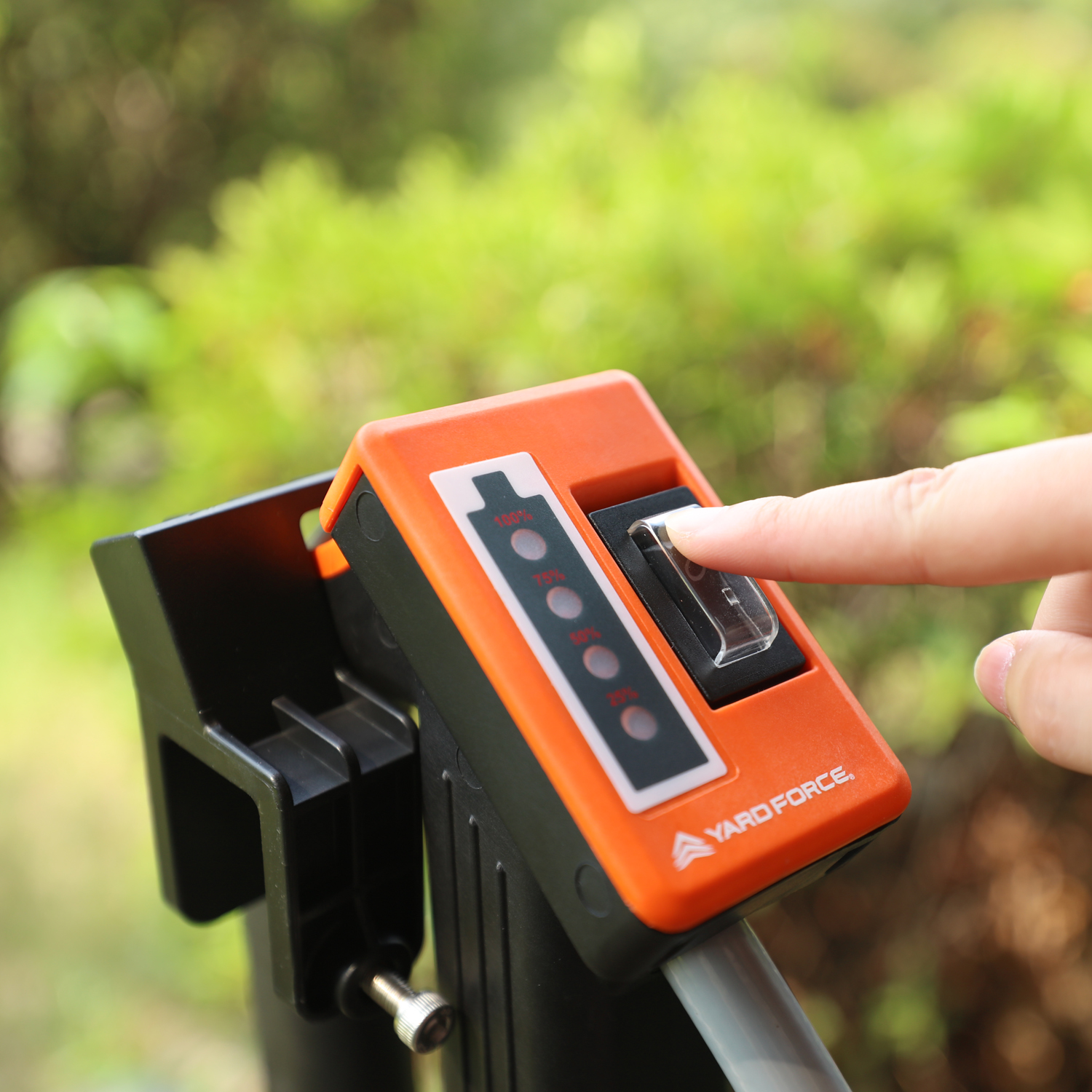 Eine Hand drückt einen Schalter an einem orangefarbenen Steuerelement mit Batteriestandsanzeige.