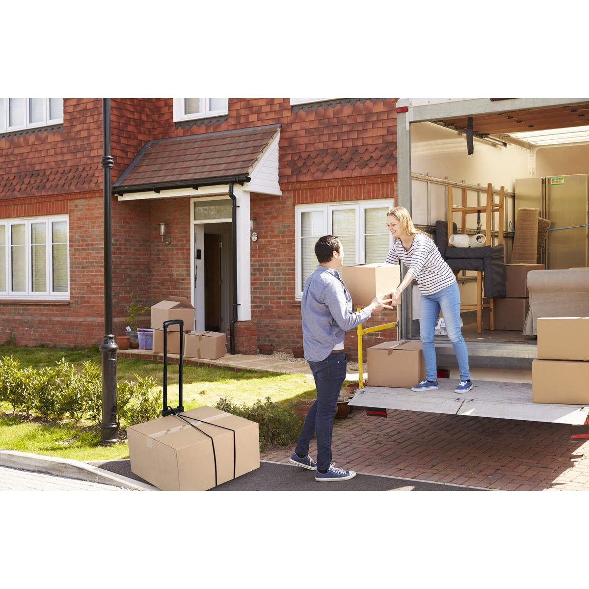 Man and woman loading boxes into a truck outside a house.